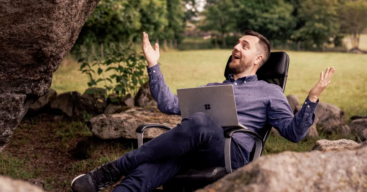 Alexander Reinhardt Kästel, daglig leder i Business Online, jubler med hendene i været i en kontorstol ute i naturen, med laptop på fanget – følelsen av å ha samsvarsmatrisen på plass før revisjonen.