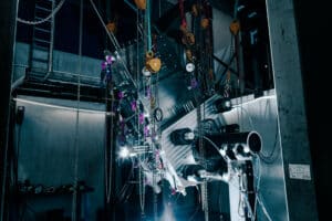 Complex mechanical test rig suspended with chains and gauges inside Izomax’s high-pressure test facility.