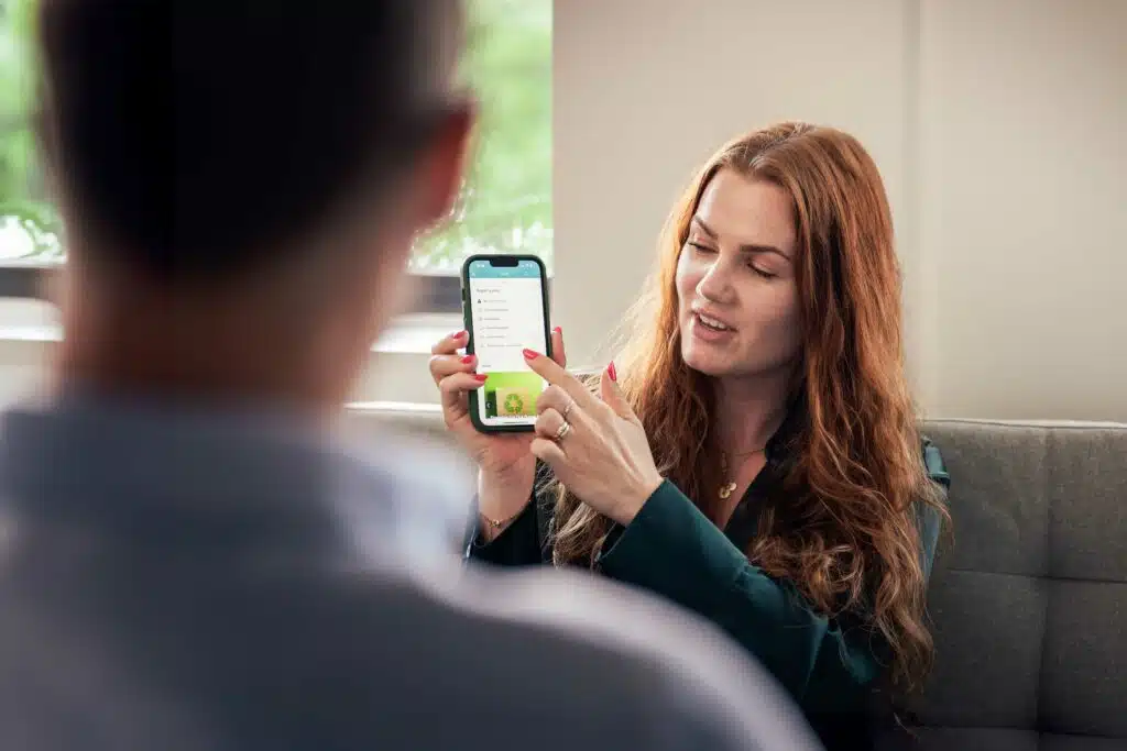 En ansatt viser prosessnivåer i Business Online på mobilen til en kollega