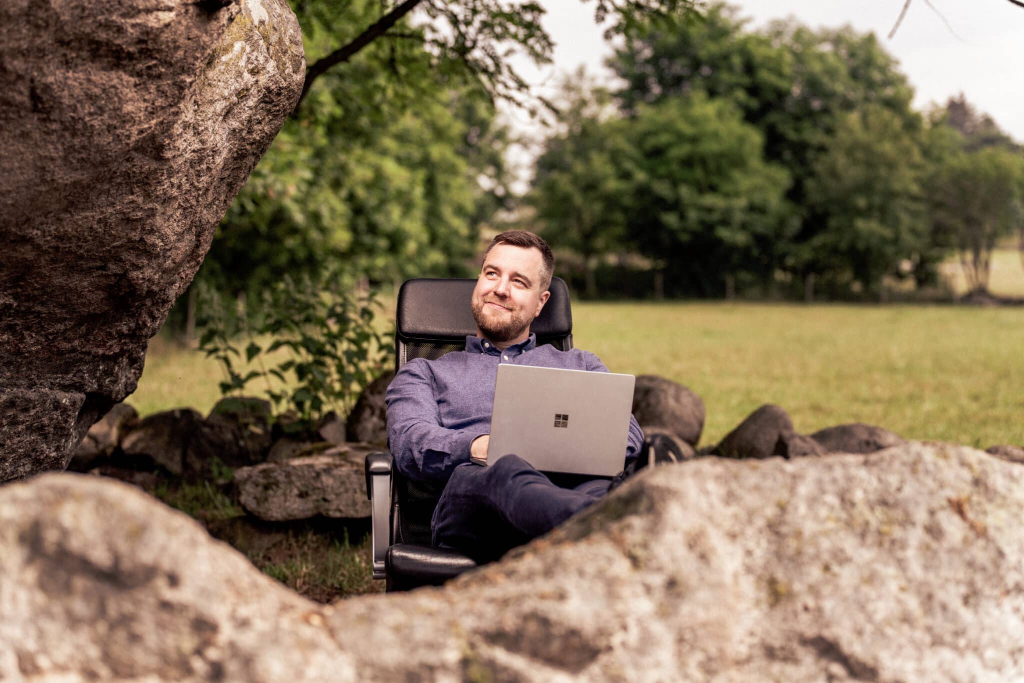 Daglig leder i Business Online sitter med laptop ute i naturen og smiler lurt mens han går gjennom en sjekkliste for ISO-sertifisering.